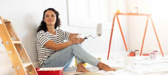 Woman taking a break from paiting a wall, smiling.